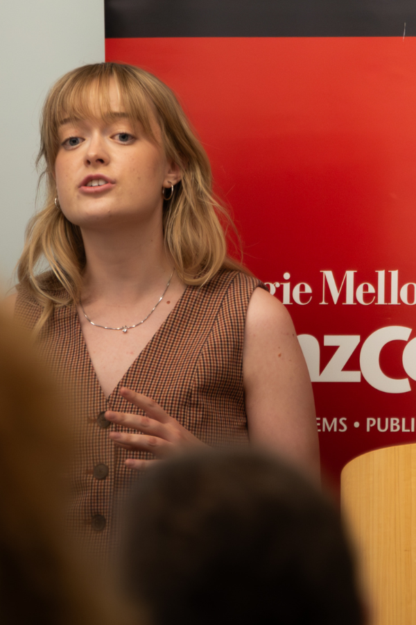 A female student in Heinz College's Master of Science in Public Policy and Management: Washington, D.C., track giving her final presentation in front of a read CMU banner.